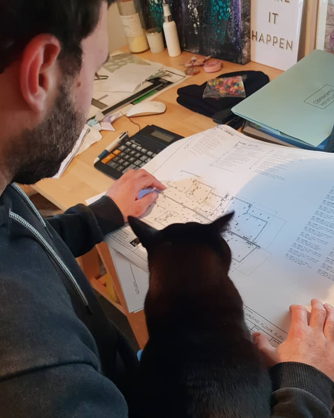 Owner of Quality Electrical Contracting, Nathan Fabiny with his pet cat working on electrical project pricing